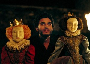 David Rizzio (Mehdi Dehbi) e seu teatro de fantoches, com as bonecas de Elizabeth I e Maria Stuart.