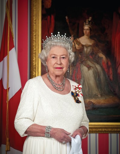 Rainha Elizabeth II tendo ao fundo o retrato de sua antecessora, a rainha Vitória.